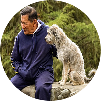 Un homme agé assis sur un mur à côté d'un chien